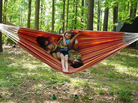Children are using the hammock while camping in a trip to the fresh nature